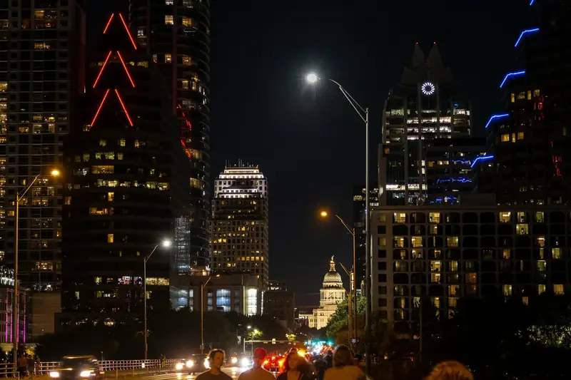 Austin street at night with the Texas State Capitol in the distance between downtown buildings